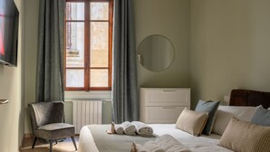A hotel room with a bed, a chair, a dresser, a round mirror, and a window with curtains. - Augustus Florence Borgo Pinti 3 min Duomo (Firenze)