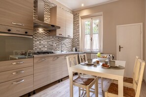 Eine moderne Küche mit Essbereich, ausgestattet mit einem Gasherd, einer Spüle und einem Fenster mit Vorhängen.