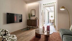 Ein modernes Wohnzimmer mit Flachbildfernseher, Holzschrank, rundem Couchtisch und einer Couch.