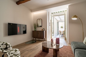 Ein modernes Wohnzimmer mit Flachbildfernseher, Holzschrank, rundem Couchtisch und einer Couch.