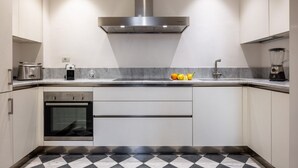 A modern kitchen with a stainless steel range hood, a built-in oven, a dishwasher, and a marble countertop. - The Loggia of Borgo SS Apostoli (Firenze)