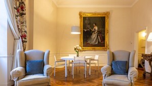A room with two armchairs, a round table, and a painting on the wall. - The Loggia of Borgo SS Apostoli (Firenze)