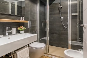 Ein modernes Badezimmer mit einer Duschkabine, einem weißen Waschbecken und einer Toilette.