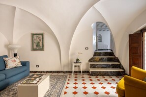 A living room with a sofa, a coffee table, a patterned rug, a staircase with a marble finish, and a framed picture on the wall. - The Renaissance Chapel by Maison Florence (Florence)