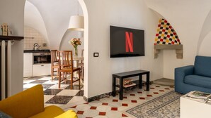 Ein Wohnzimmer mit Fernseher, einer Couch, einem Couchtisch und einem gemusterten Boden.