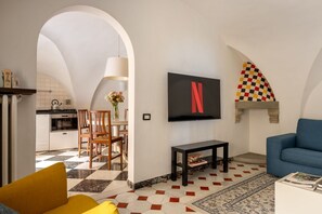 A living room with a TV, a sofa, a coffee table, and a patterned floor. - The Renaissance Chapel by Maison Florence (Florence)