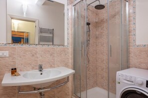 Ein Badezimmer mit Waschbecken, Duschkabine aus Glas und Waschmaschine.