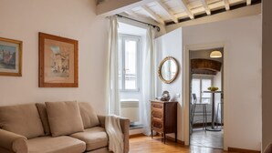 A living room with a sofa, a wooden cabinet, a mirror, and a dining area with chairs and a table. - Santa Croce Historic Apartment by Maison Florence (Florence)