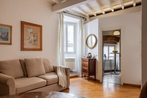 A living room with a sofa, a wooden cabinet, a mirror, and a dining area with chairs and a table. - Santa Croce Historic Apartment by Maison Florence (Florence)