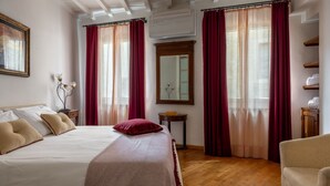 A hotel room with a bed, a chair, a mirror, and a shelf with towels. - Santa Croce Historic Apartment by Maison Florence (Florence)