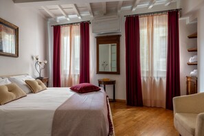 A hotel room with a bed, a chair, a mirror, and a shelf with towels. - Santa Croce Historic Apartment by Maison Florence (Florence)