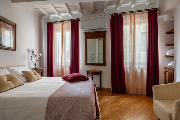 Ein Hotelzimmer mit Bett, Sessel, Spiegel und Ablagefläche mit Handtüchern.