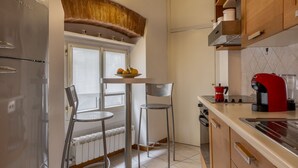 A kitchen with a refrigerator, a coffee maker, and a window with a view. - Santa Croce Historic Apartment by Maison Florence (Florence)
