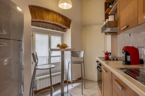 A kitchen with a refrigerator, a coffee maker, and a window with a view. - Santa Croce Historic Apartment by Maison Florence (Florence)
