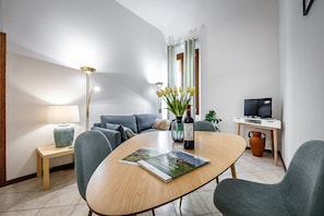Ein modernes Wohnzimmer mit einem runden Holztisch, einer Couch, einem Fernseher und einer Lampe.