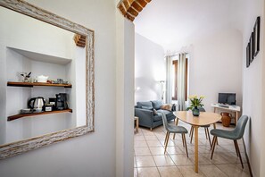 Ein Wohnzimmer mit einer Couch, einem Couchtisch und einem Fernseher. Es gibt eine Essecke mit Tisch und Stühlen.
