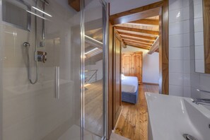 A modern bathroom with a glass shower enclosure, a white bathtub, and wooden flooring. - A Romantic Home—Charm and Elegance in the Heart of Florence   (Firenze)