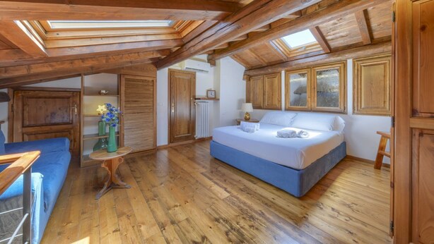 Une chambre aménagée dans les combles, avec un lit, un canapé et une petite table.