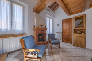 A living room with a fireplace, wooden furniture, and a tiled floor. - Romantic Home - Charm and Elegance in the Heart of Florence (Firenze)