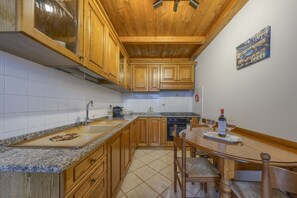 A kitchen with wooden cabinets, a granite countertop, a dining table with chairs, and a painting on the wall. - A Romantic Home—Charm and Elegance in the Heart of Florence   (Firenze)
