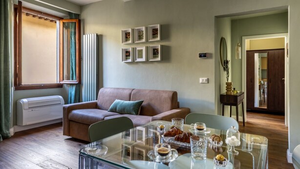 A living room with a glass coffee table, a brown leather sofa, and framed pictures on the wall. - Geometric Design Suite by Maison Florence (Florence)