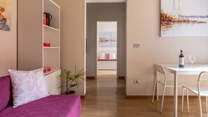 Una sala de estar moderna con un sofá, una mesa de comedor con sillas, una estantería y un cuadro en la pared.