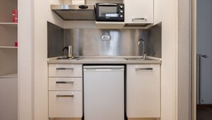 Cocina compacta con lavavajillas integrado, microondas y pileta de acero inoxidable.