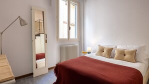 A bedroom with a bed, a bedside lamp, a mirror, a window, and a radiator. - Like a Local Borgo San Jacopo By Maison Florence (Firenze)