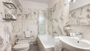 A bathroom with a toilet, bidet, bathtub, and sink, all with marble walls and fixtures. - Like a Local Borgo San Jacopo By Maison Florence (Firenze)