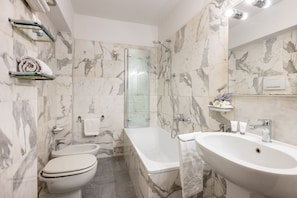 Ein Badezimmer mit Toilette, Bidet, Badewanne und Waschbecken, alles mit Marmorwänden und Armaturen.