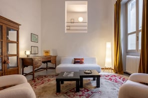 Ein Zimmer mit einem Bett, einem Schreibtisch, einer Lampe, einem Heizkörper und einem Fenster mit Vorhängen.