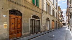 A narrow street with historic buildings, a double wooden door, and a metal gate. - Borgo Pinti Medieval Apartment (Firenze)