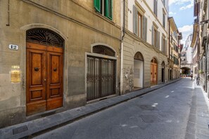 A narrow street with historic buildings, a double wooden door, and a metal gate. - Borgo Pinti Medieval Apartment (Firenze)