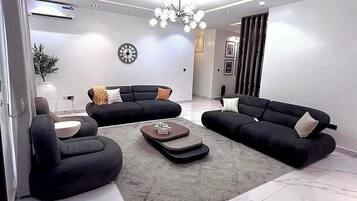 A modern living room with a sectional sofa, a coffee table, and a chandelier.