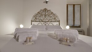 Un lit bien fait, agrémenté d’une tête de lit décorative, de deux lampes de chevet et de serviettes posées sur le lit.