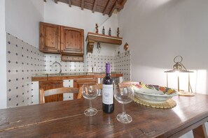 A kitchen with wooden cabinets, a wine bottle, two glasses, and a decorative plate on the counter. - Welcome to our enchanting medieval apartment located in the heart of Florence’s historic center, just 200 meters from Piazza della Signoria.This elegant apartment, perfect for families and couples, will offer you a unique and comfortable experience.The (Firenze)
