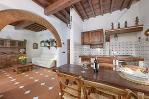 Ein rustikales Interieur mit Essbereich, Küche und Wohnbereich, gekennzeichnet durch freiliegende Holzbalken, Fliesenböden und traditionelle Dekoration.