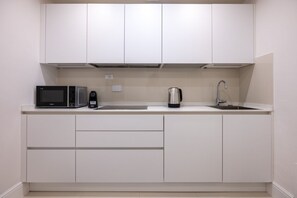 A modern kitchen with white cabinets, a microwave, a coffee maker, and a sink. - The White House - Home of the Frescoes (Firenze)