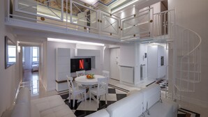 Uma sala de estar ampla com pé direito alto, escada e televisão de tela plana.