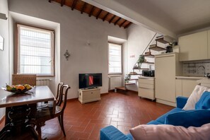 Ein gemütlicher Wohnbereich mit Essplatz, Fernseher, Küchenzeile und einem blauen Sofa.