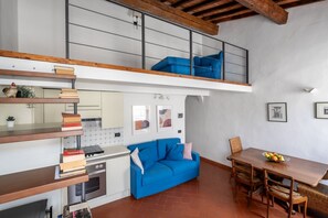 Eine moderne Küche mit blauem Sofa, Esstisch und einer Erschliessung mit blauem Schlafsofa.