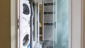 Un cuarto de lavandería con lavadoras apiladas y un box de ducha de vidrio.