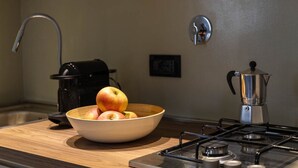 Una cocina con un frutero, una cafetera y una estufa.