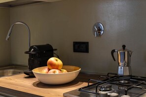 Eine Küche mit einer Obstschale, einer Kaffeemaschine und einem Herd.