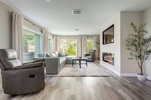 A modern living room with a sofa, armchair, and a fireplace.
