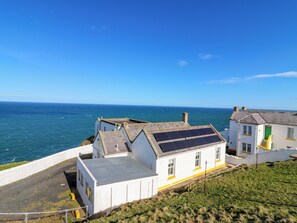 Un bâtiment situé sur la côte, doté d’un toit plat, de murs blancs et d’une porte verte.
