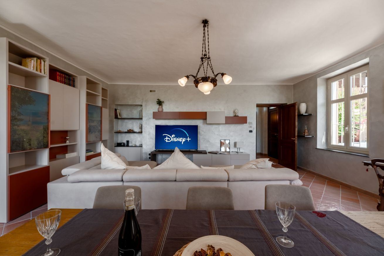 A modern living room with a sofa, dining table, and a TV displaying the Disney+ logo.