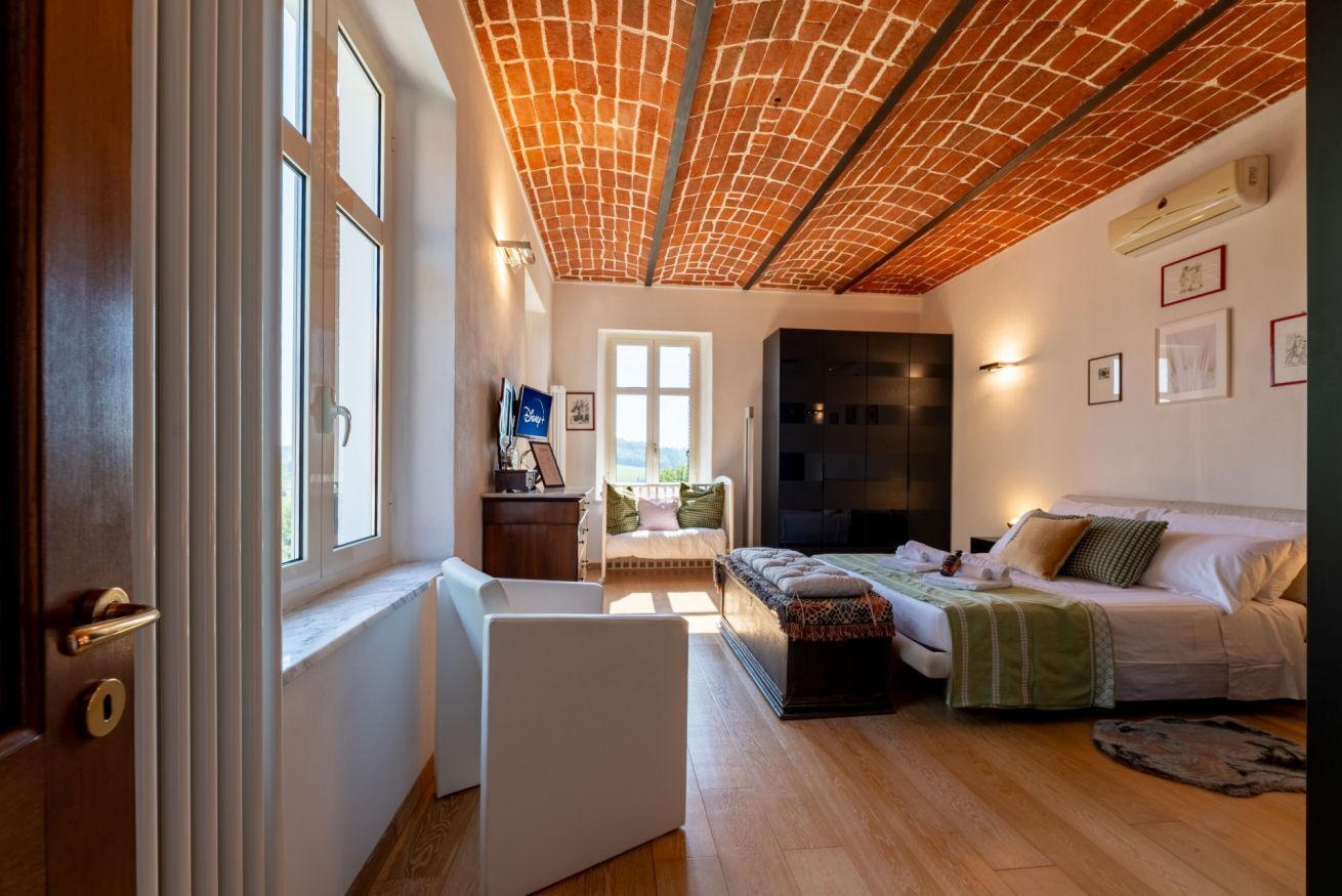 Une chambre avec un plafond en briques, un lit, un bureau et une fenêtre.