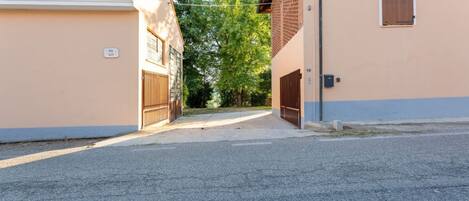 Un camino de entrada cerrado por una reja que lleva a un edificio con una puerta de garaje y un ventanal.