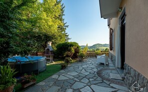 Eine Steinterrasse mit Whirlpool, Gartenmöbeln und Blick auf die Landschaft.